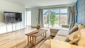 A living room with a wooden coffee table, a sofa, and a television on a stand.
