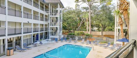 A pool area with lounge chairs and a clear blue pool.