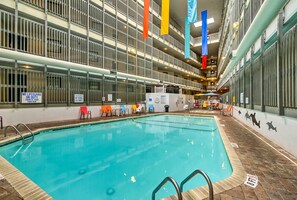 Piscina interna com várias pistas de natação, rodeada por teto alto com vigas estruturais aparentes e corrimãos.