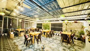 Een binnenterras met tafels en stoelen, een vloer met een patroon en een plafond met een rasterstructuur.
