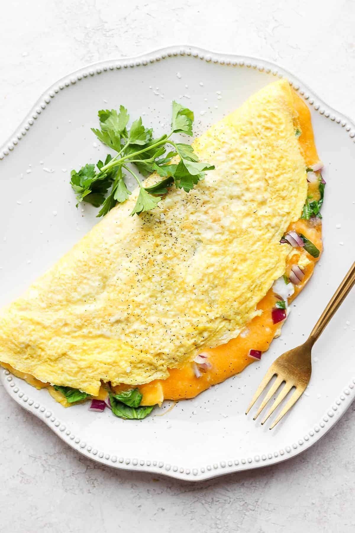 A plate with an omelette, garnished with parsley, and a fork beside it.