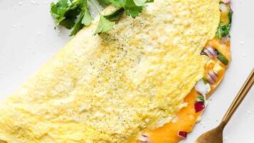 A plate with an omelette, garnished with parsley, and a fork beside it.