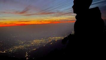 Eine Silhouette einer Person, die auf eine Stadtlandschaft bei Sonnenuntergang blickt.