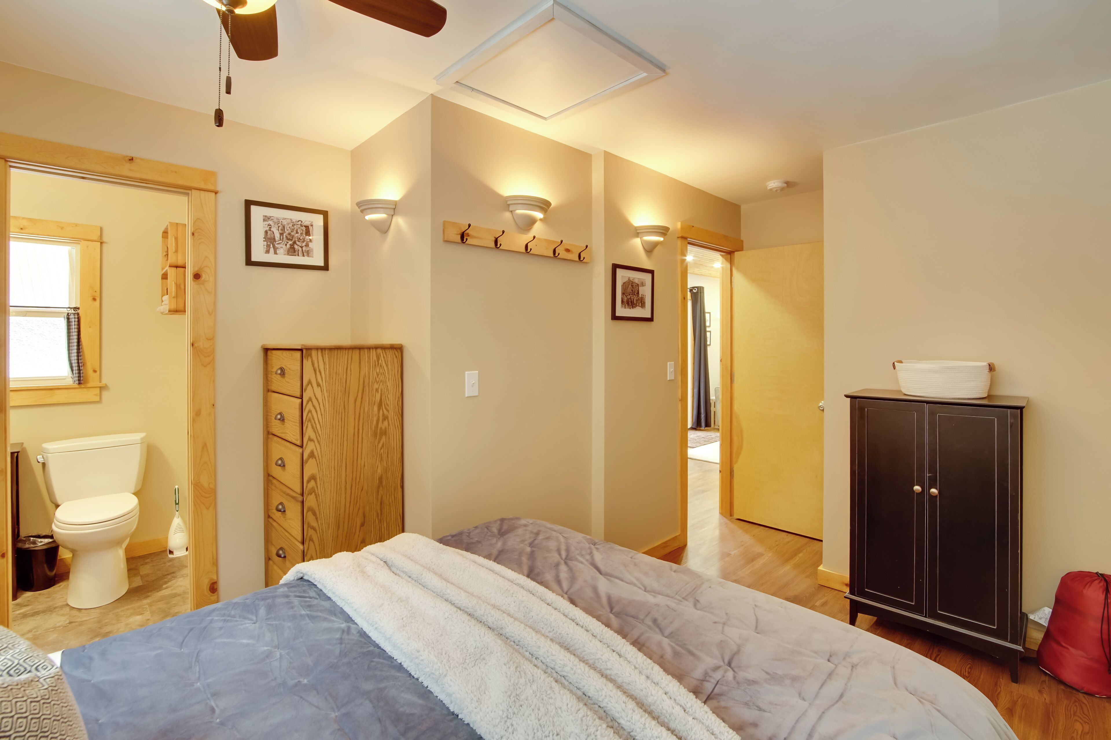 Un dormitorio con cama, armario de madera y baño con inodoro y lavamanos.