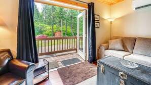 A cozy room with a leather sofa, a wooden ceiling, and a large window with curtains. - Cle Elum Cabin on the Yakima River! (Cle Elum)