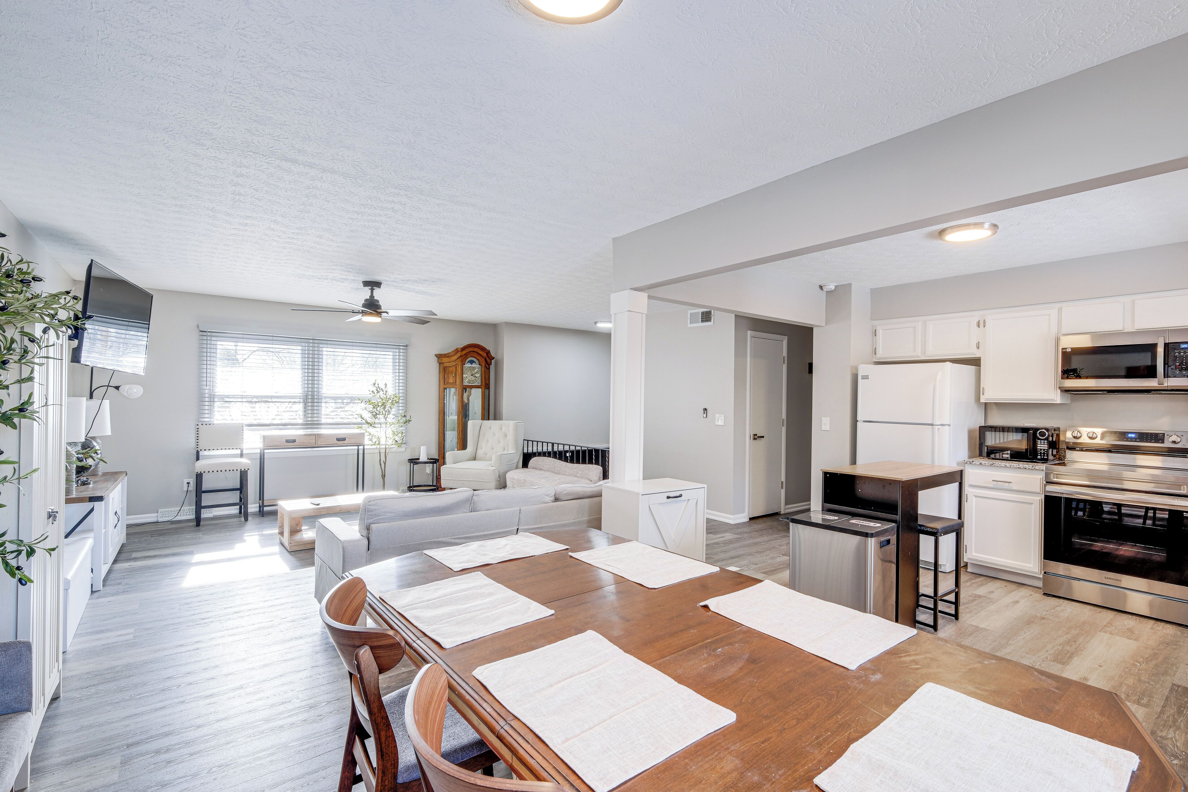 A modern kitchen with white cabinets, stainless steel appliances, and a wooden dining table with placemats.