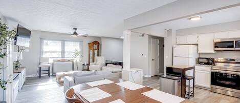 A modern kitchen with white cabinets, stainless steel appliances, and a wooden dining table with placemats.