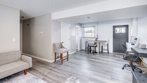 A modern apartment with a grey sofa, a wooden chair, a dining table with chairs, and a black office chair. - 3 Mi to Cuyahoga Valley NP: Fairlawn Family Home! (Akron)