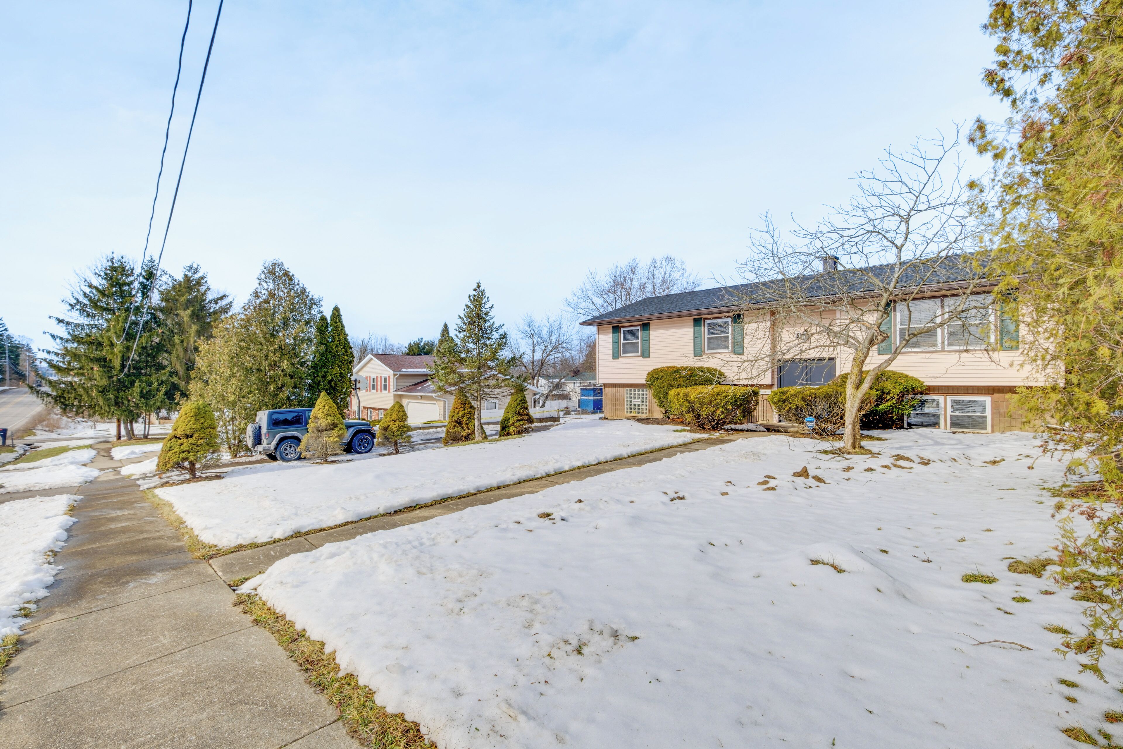 Un quartier résidentiel avec des maisons, un trottoir et une cour enneigée.