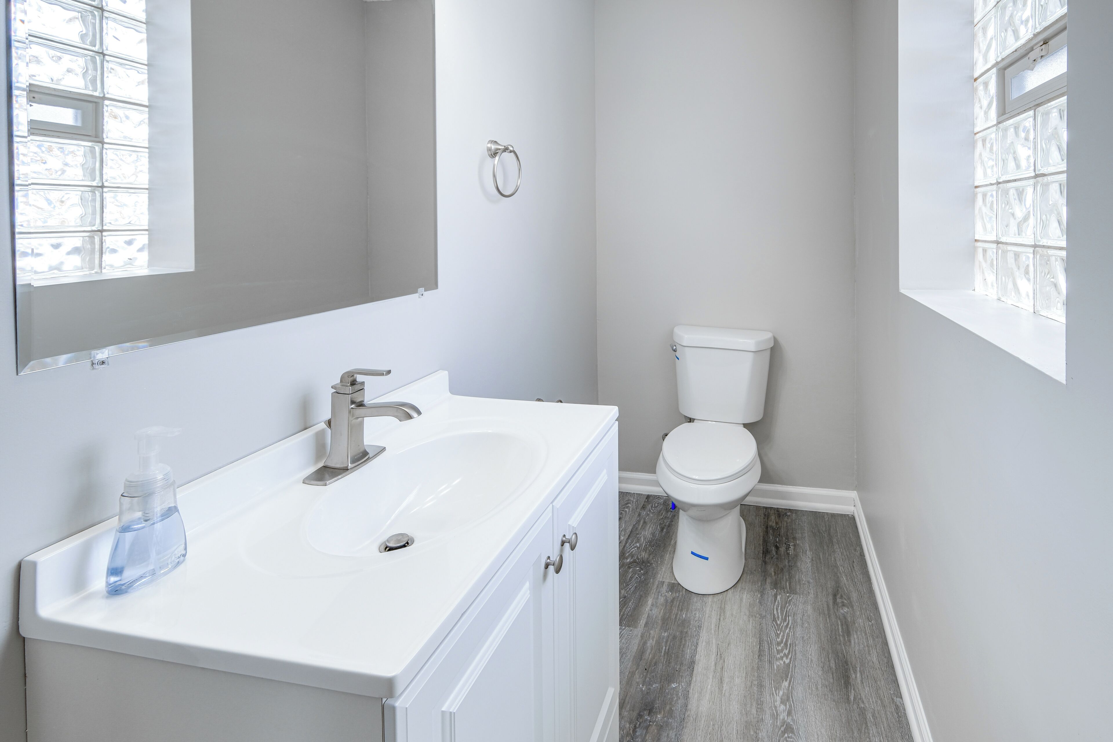 Un baño con lavamanos, espejo y retrete blancos.