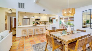 A modern kitchen with a central island, bar stools, and a dining table with chairs. - Half-mi to Private Beach: Floridana Beach Getaway (Melbourne Beach)