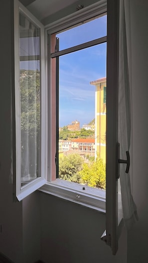 Une fenêtre donnant sur des immeubles et de la verdure.