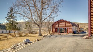 A rustic barn-style building with a large door and windows, surrounded by a fenced area with rocks and a tree. - 2 Mi to Main Street: Mtn-view Escape in Lander! (Lander)