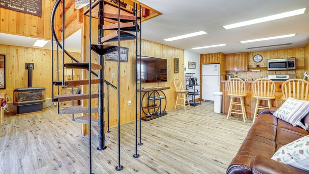 A cozy cabin interior with a spiral staircase, wooden floors, a fireplace, a kitchen area, and a comfortable seating area. - 2 Mi to Main Street: Mtn-view Escape in Lander! (Lander)