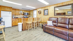 A kitchen with wooden cabinets, a refrigerator, and a microwave. There are three wooden chairs and a brown leather couch. - 2 Mi to Main Street: Mtn-view Escape in Lander! (Lander)