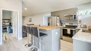 A modern kitchen with a central island, bar stools, a microwave, a refrigerator, and an oven. - Pasture & Pond Views: Lovely Lutz Apartment (Lutz)
