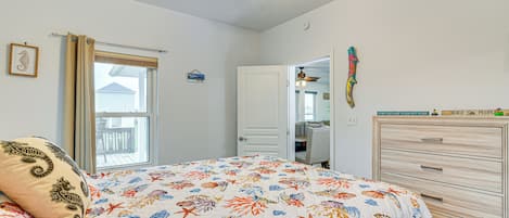 A bedroom with a bed, a ceiling fan, a window with curtains, a door, and a dresser.