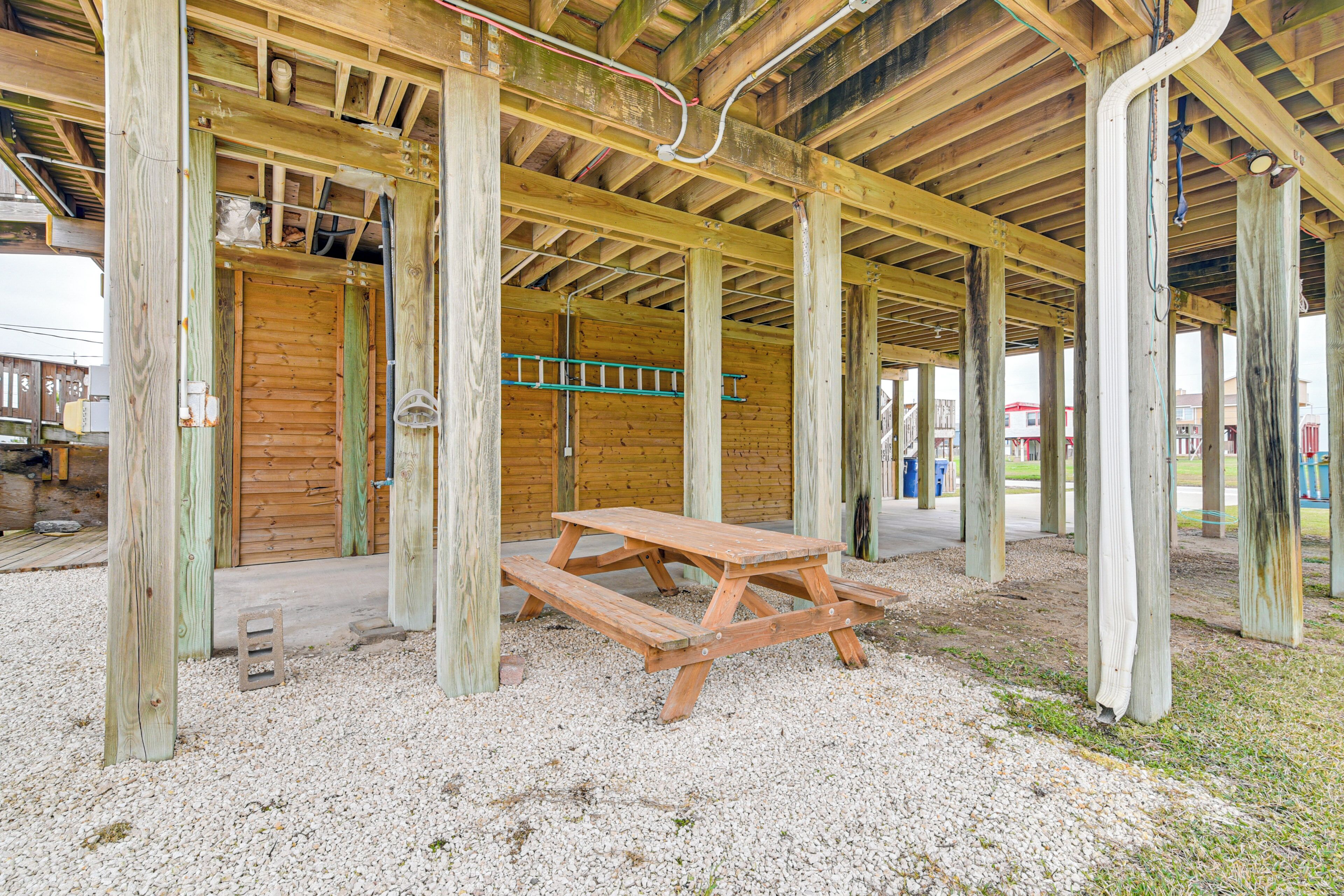 A wooden structure with a picnic table in the center, surrounded by gravel.