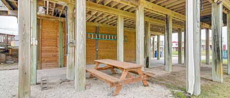 A wooden structure with a picnic table in the center, surrounded by gravel.
