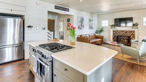 A modern kitchen with stainless steel appliances, a large island, and a fireplace.