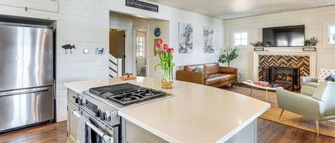 A modern kitchen with stainless steel appliances, a large island, and a fireplace.