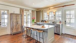 A kitchen with a central island, bar stools, wooden cabinets, and a dishwasher.
