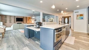 A spacious kitchen with a central island, built-in appliances, and a brick accent wall. - 3 Mi to Dtwn Alpena: Family Home w/ Yard! (Alpena)