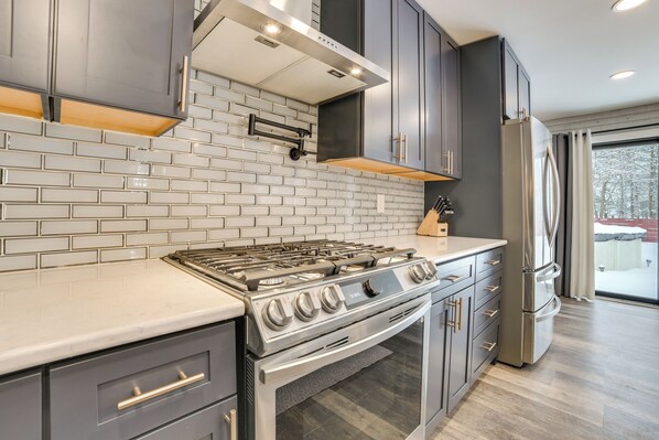A modern kitchen with grey cabinets, a stainless steel stove, and a built-in oven.