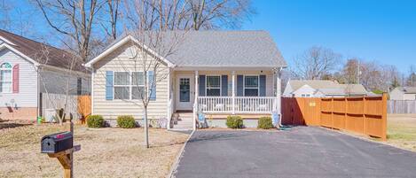 A single-story house with a front porch, a mailbox, and a wooden fence.
