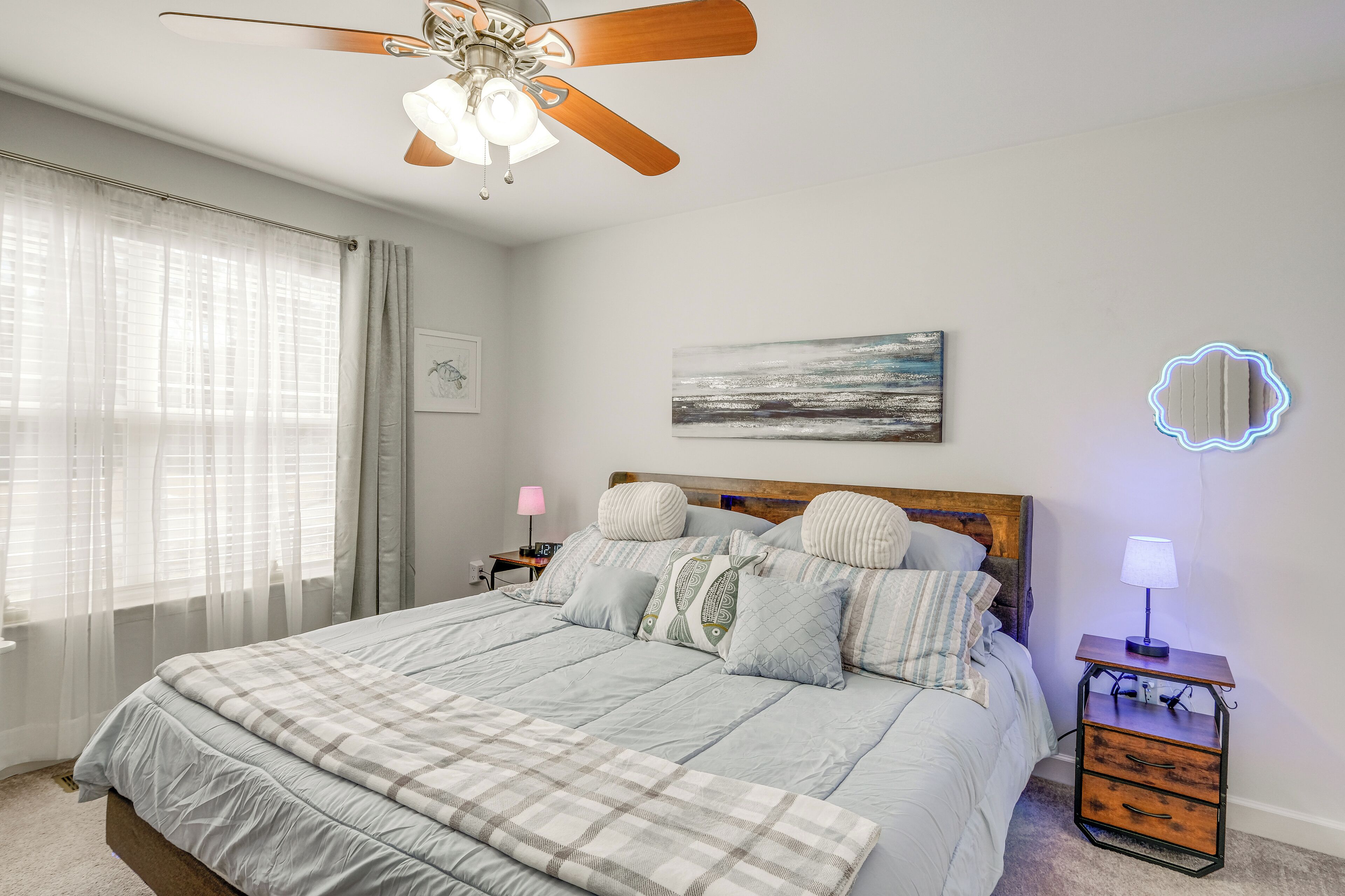 Ein Schlafzimmer mit Bett, Nachttisch, Deckenventilator und Wandlampe.