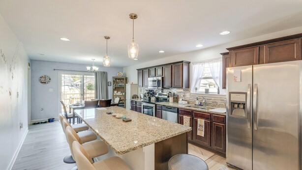 A modern kitchen with granite countertops, stainless steel appliances, and a central island with bar stools. - 1 Mi to Colonial Beach Boardwalk: Home w/ Fire Pit (Colonial Beach)