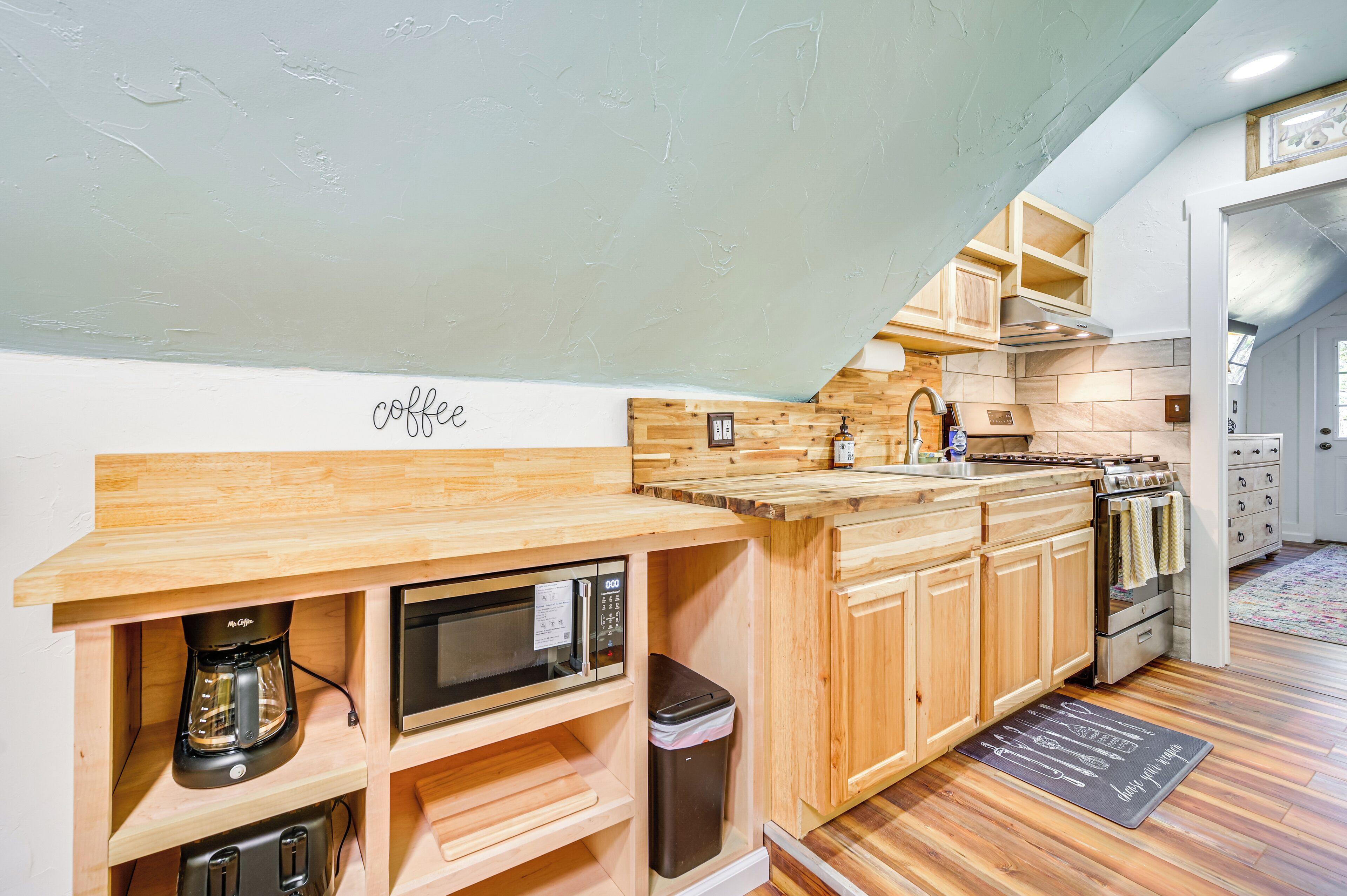 A kitchen with wooden cabinets, a built-in microwave, and a coffee maker.