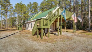 A rustic cabin with a green staircase and a porch, surrounded by tall pine trees. - Boat Dock & Ramp: Upwind Acres Guesthouse! (Aurora)