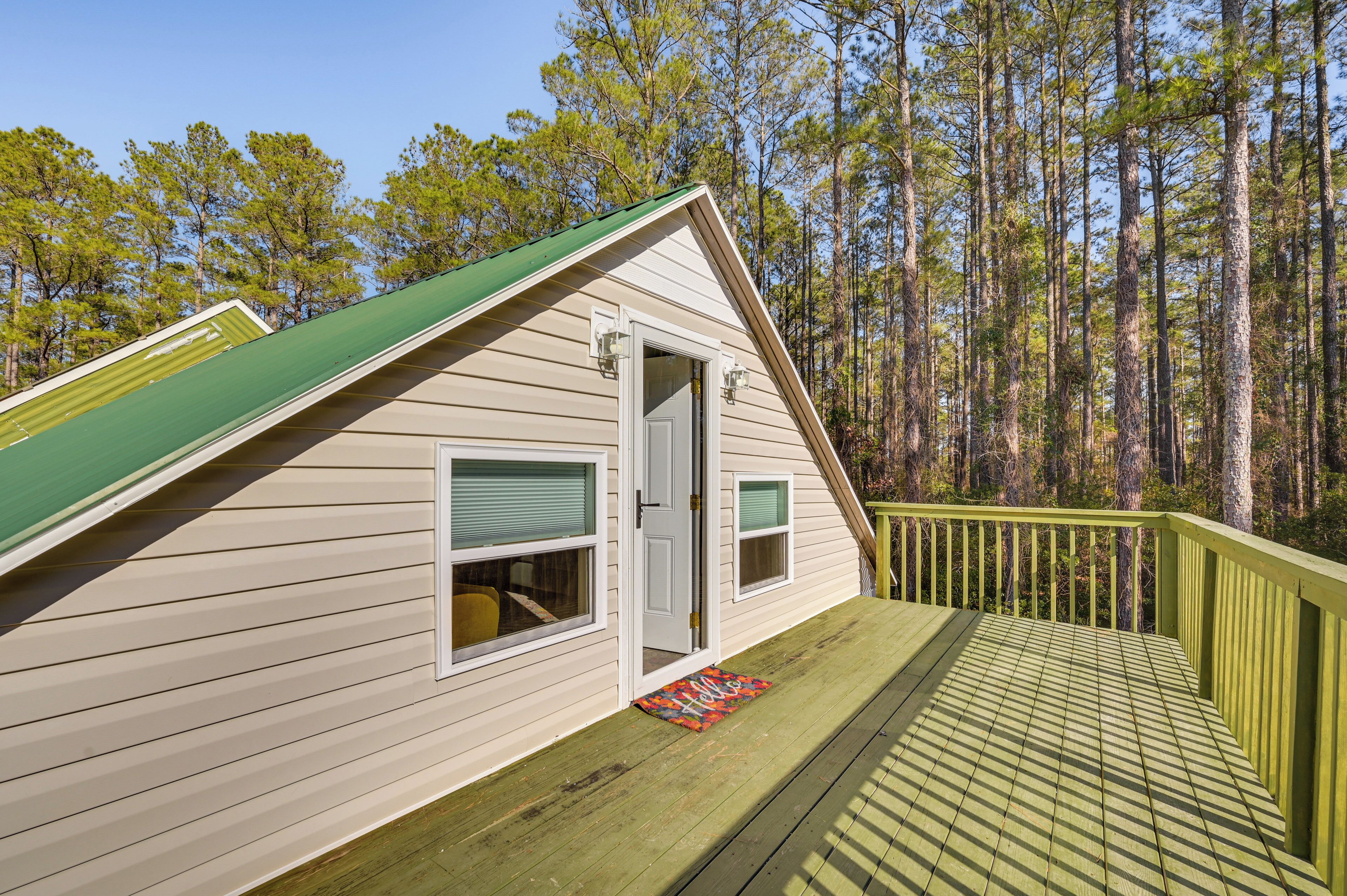 A cabin with a green roof, a deck, and a door with a window.