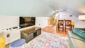 A spacious living area with a large flat-screen TV, wooden furniture, and a colorful rug. - Boat Dock & Ramp: Upwind Acres Guesthouse! (Aurora)