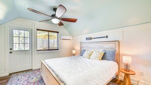 A bedroom with a bed, a ceiling fan, a window, and a nightstand with a lamp. - Boat Dock & Ramp: Upwind Acres Guesthouse! (Aurora)