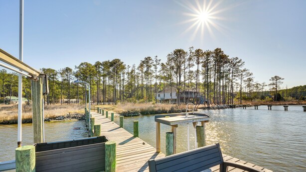 A wooden dock extending over a calm body of water, with a bench and a small table. - Boat Dock & Ramp: Upwind Acres Guesthouse! (Aurora)