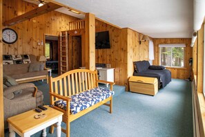 A wooden cabin interior with a sofa, a bench, a desk, and a bed. - Lakefront Home w/ Seasonal Dock in Limerick! (Limerick)