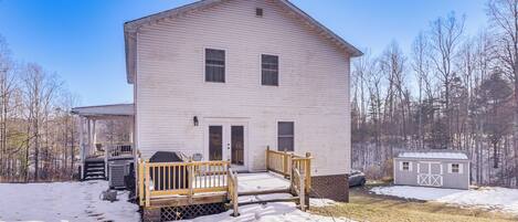 A two-story white house with a wooden porch, a garage, and a small shed.