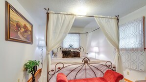 A bedroom with a four-poster bed, a red chair, a potted plant, and a painting on the wall. - 1 Mi to Dtwn Mountain View: Home w/ Deck (Mountain View)