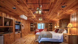 A cabin-style bedroom with a wooden interior, a bed, a desk, and a bookshelf. - Ramona Point on 4th Lake (Old Forge)