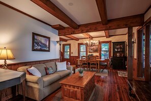 Un salon chaleureux avec un plafond en bois, un canapé, une table basse et une table à manger avec des chaises.