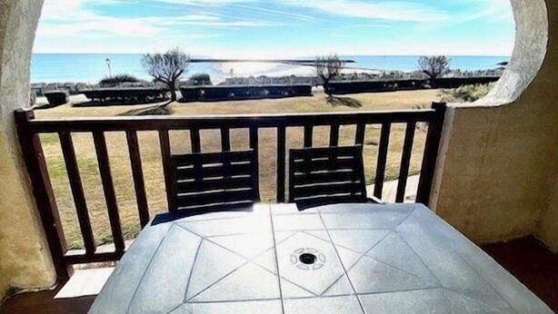 Un patio con mesa y sillas, y un ventanal de arco que da a un paisaje.