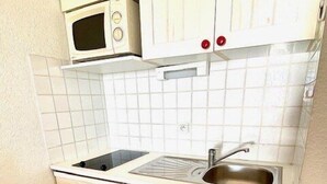 Cocina compacta con lavadora, microondas y pileta.