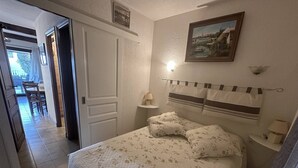 Un dormitori amb un llit, taules de nit, una pintura i una porta que condueix a una altra habitació.