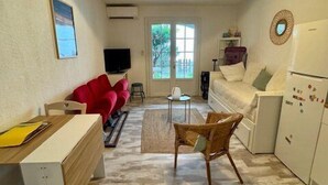 A compact living space with a dining area, a sofa, a TV, and a kitchen area with a refrigerator. - Studio-type apartment with terrace and parking space (SAINTES MARIES DE LA MER)