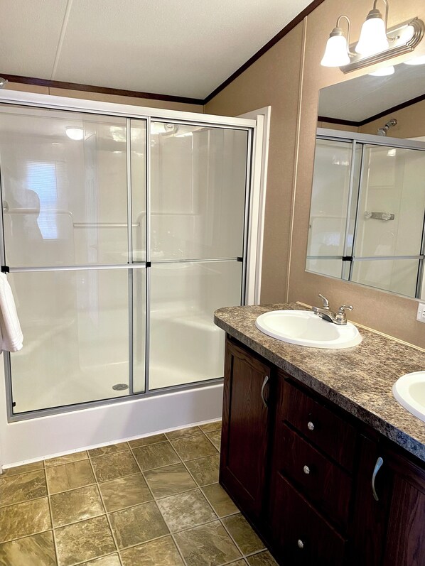 A bathroom with a glass-enclosed shower, a sink, and a vanity with drawers. - Family Friendly Site With 24 Hour Access to Dunes (Waynoka)