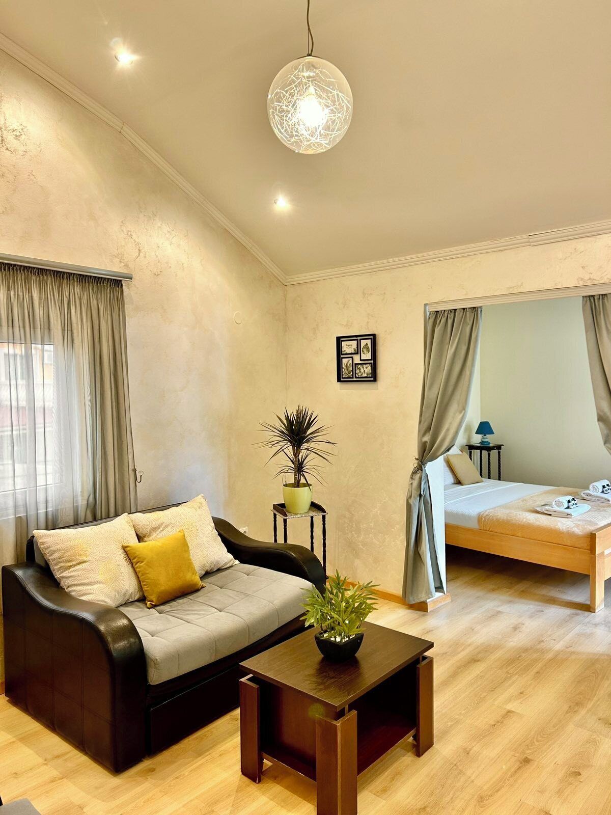 A modern living room with a sofa, a coffee table, a bed, and a hanging light fixture.