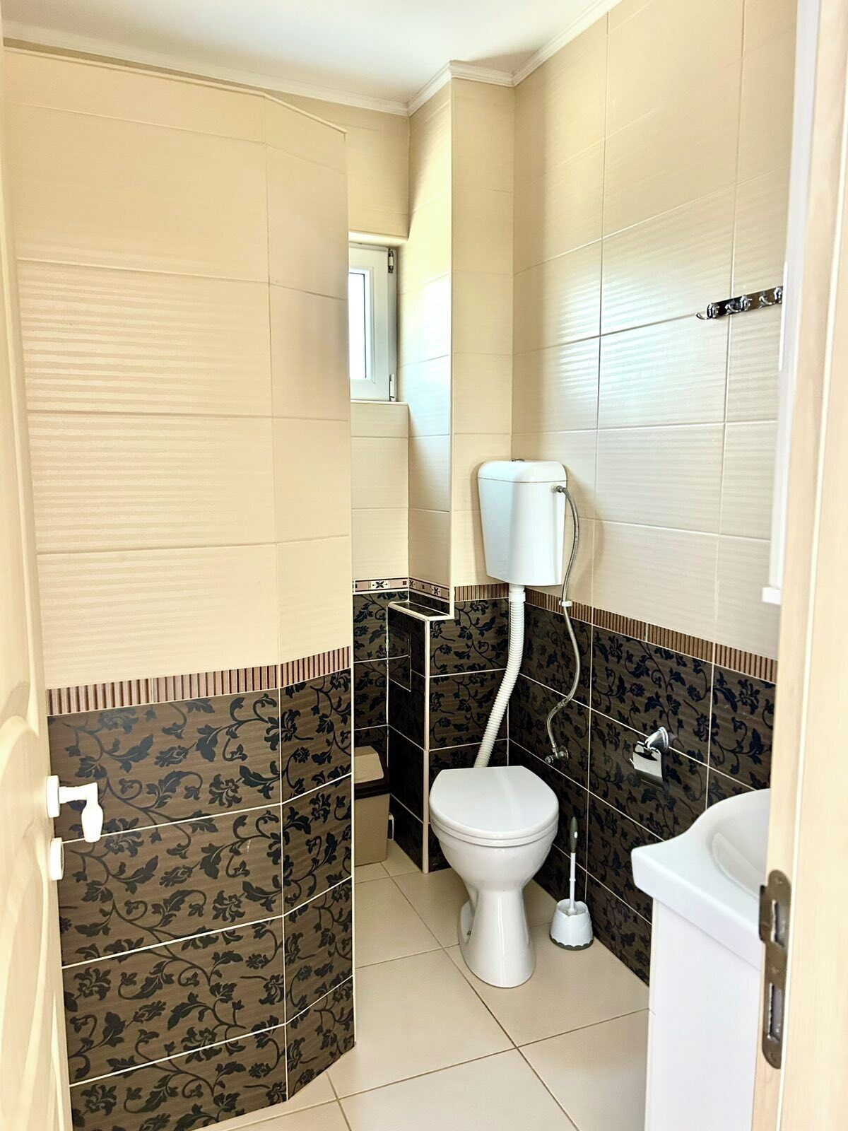 A small, compact bathroom with a toilet, a sink, and a shower area.