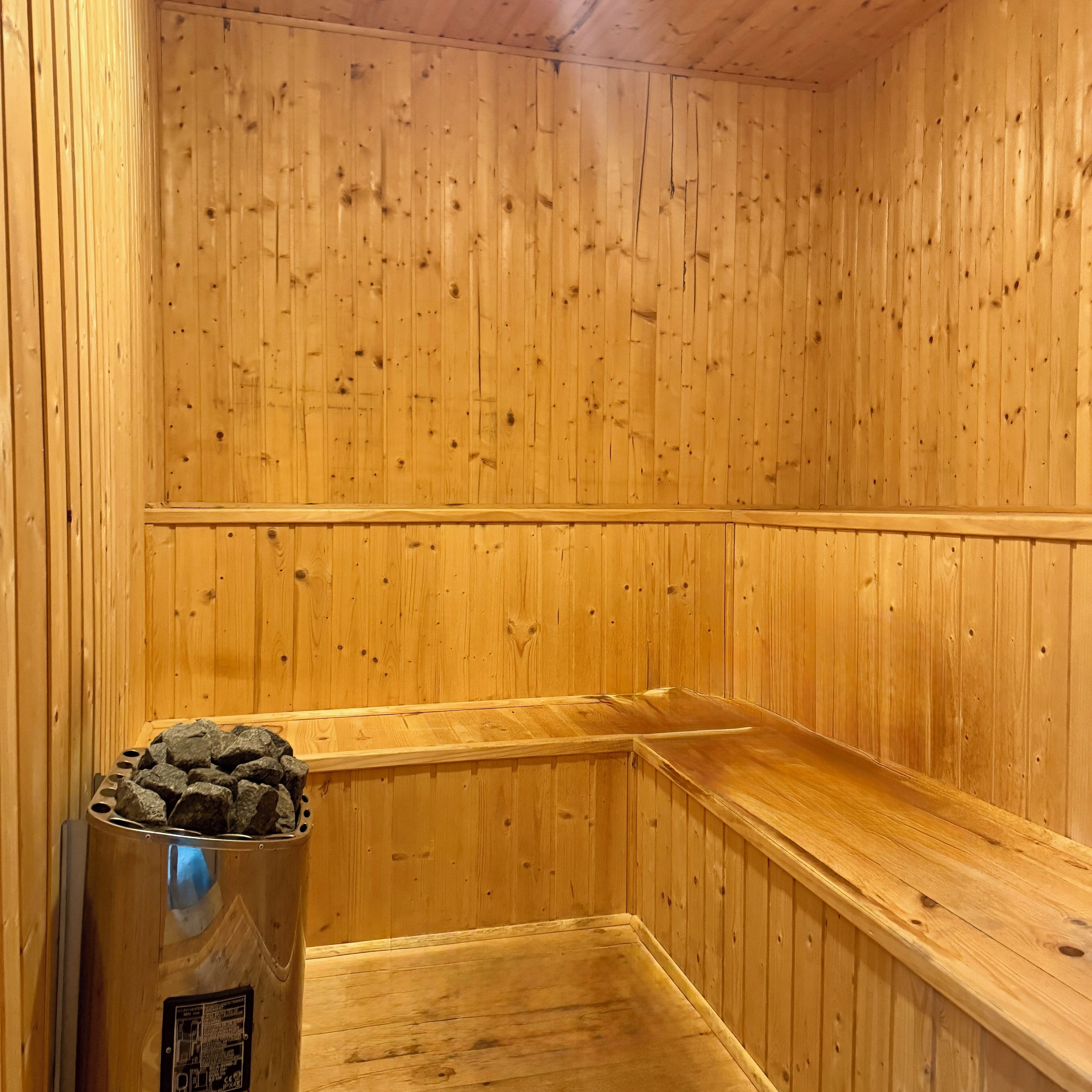 Eine Holzsauna mit einer Bank und einem Behälter mit Steinen.